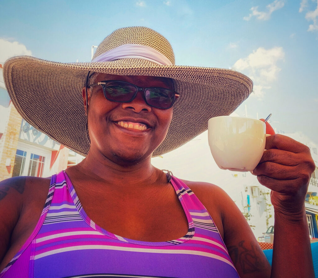Mel smiling while holding cup of coffee in Greece
