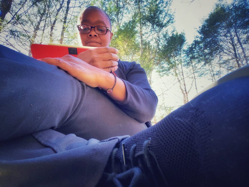 Mel reading tablet in woods