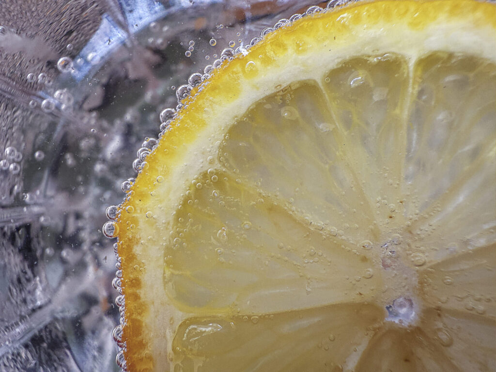 Bubbles cling to a juicy lemon slice in this refreshing macro shot that highlights the playful textures and crisp clarity of citrus