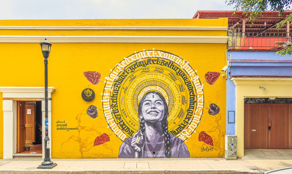 A mural of a young woman with a keyhole in her forehead, smiling beneath a halo of words on a bright yellow wall
