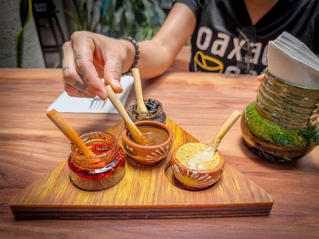Three mole sauces on a triangular cutting board with the tour guide’s hands mid-explanation