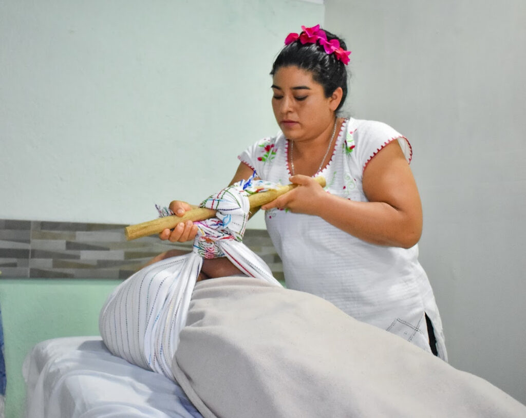 A massage therapist providing a traditional mezcal and herb massage
