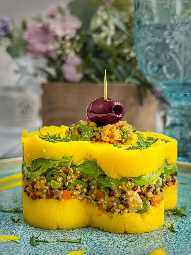 Causa Rellana with quinoa vegetable mixture, topped with an olive